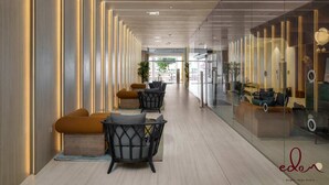 Un hall d’hôtel moderne avec un long couloir, des espaces de détente et des murs en verre.