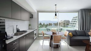 Une cuisine moderne avec un coin repas, un canapé et une vue sur un immeuble et des montagnes.
