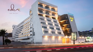 Um hotel moderno com vários andares, um destaque com a inscrição 'SEA SIDE' e fachada bem iluminada.