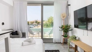Habitació d'hotel moderna amb llit, escriptori, cadira, balcó i vistes, i un televisor.