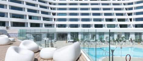Ett modernt hotell med poolområde, flera våningar och utomhusservering.
