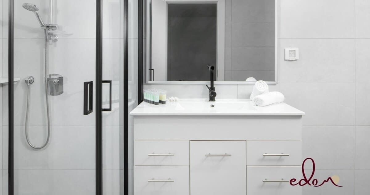A modern bathroom with a glass shower enclosure, a white vanity with a mirror, and a towel rack.