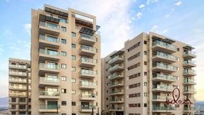 Um edifício residencial moderno, com vários andares, varandas, janelas amplas e painéis solares.