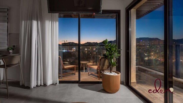 Quarto moderno com uma grande porta de vidro deslizante que dá para uma varanda com vista para a cidade.