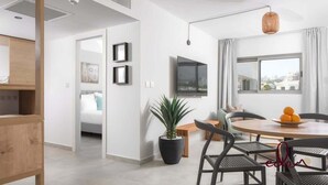 Un salon moderne comprenant un coin repas, une grande fenêtre et un téléviseur à écran plat fixé au mur.