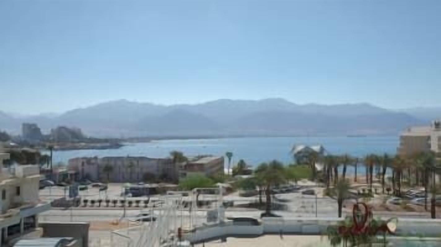 Un paysage urbain côtier offrant une vue sur la mer et les montagnes au loin.