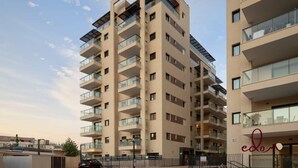Un edificio residenziale a più piani con balconi, cielo sereno e un cartello con la scritta 'edon'.