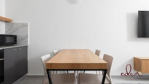 Una cucina moderna con un tavolo e sedie di legno, un forno a microonde e un armadietto.