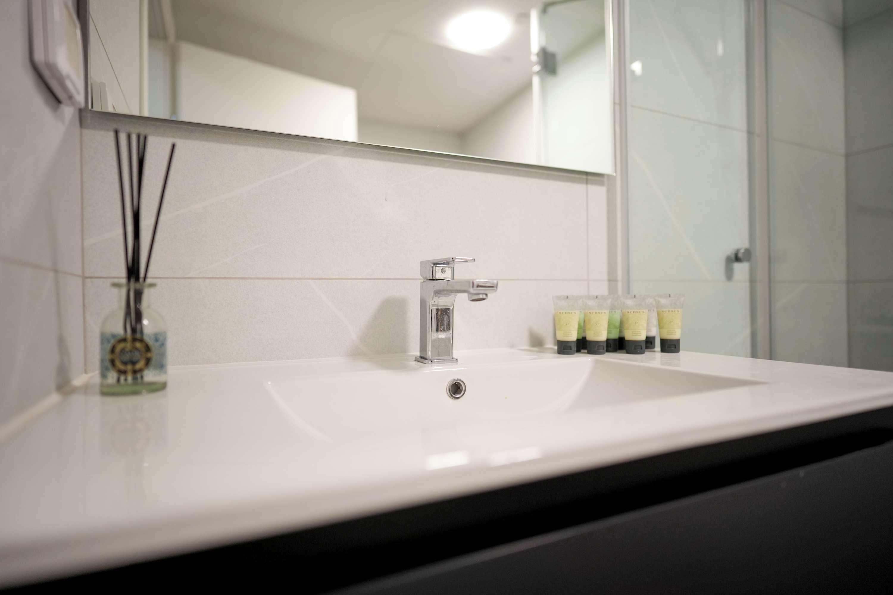 A bathroom with a white sink, a mirror, and a glass shower enclosure.