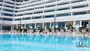 Ett modernt hotell med en stor inomhuspool, solstolar och en flervåningsbyggnad med balkonger.