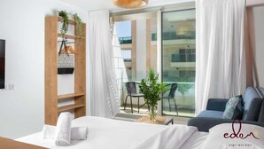 Una habitación de hotel moderna con una cama, un balcón con una silla y una estantería de madera con plantas.