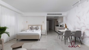 A modern bedroom with a large bed, bedside tables, a desk, and chairs. - סוויטה מעוצבת במתחם סיי סייד - By Edomlux (Eilat)