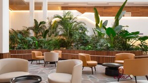 Een moderne, overdekte lounge met zitplaatsen en een weelderige groene plantenwand.
