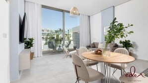 Uma sala de estar moderna com área de jantar, janelas amplas e varanda com mobiliário de exterior.