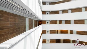 A multi-level interior with a modern design, featuring a central corridor with wooden paneling and white walls, and a logo in the bottom right corner. - דירת 2 חדרי שינה וסלון 50 מטר מהים- By Edom (Eilat)