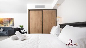 Une chambre à coucher moderne avec un grand lit, une tête de lit sombre et une armoire en bois.