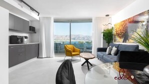Un salon moderne avec un canapé, un fauteuil jaune et une table basse en verre.