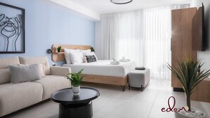 Quarto moderno com cama, sofá, mesa de centro e televisão.