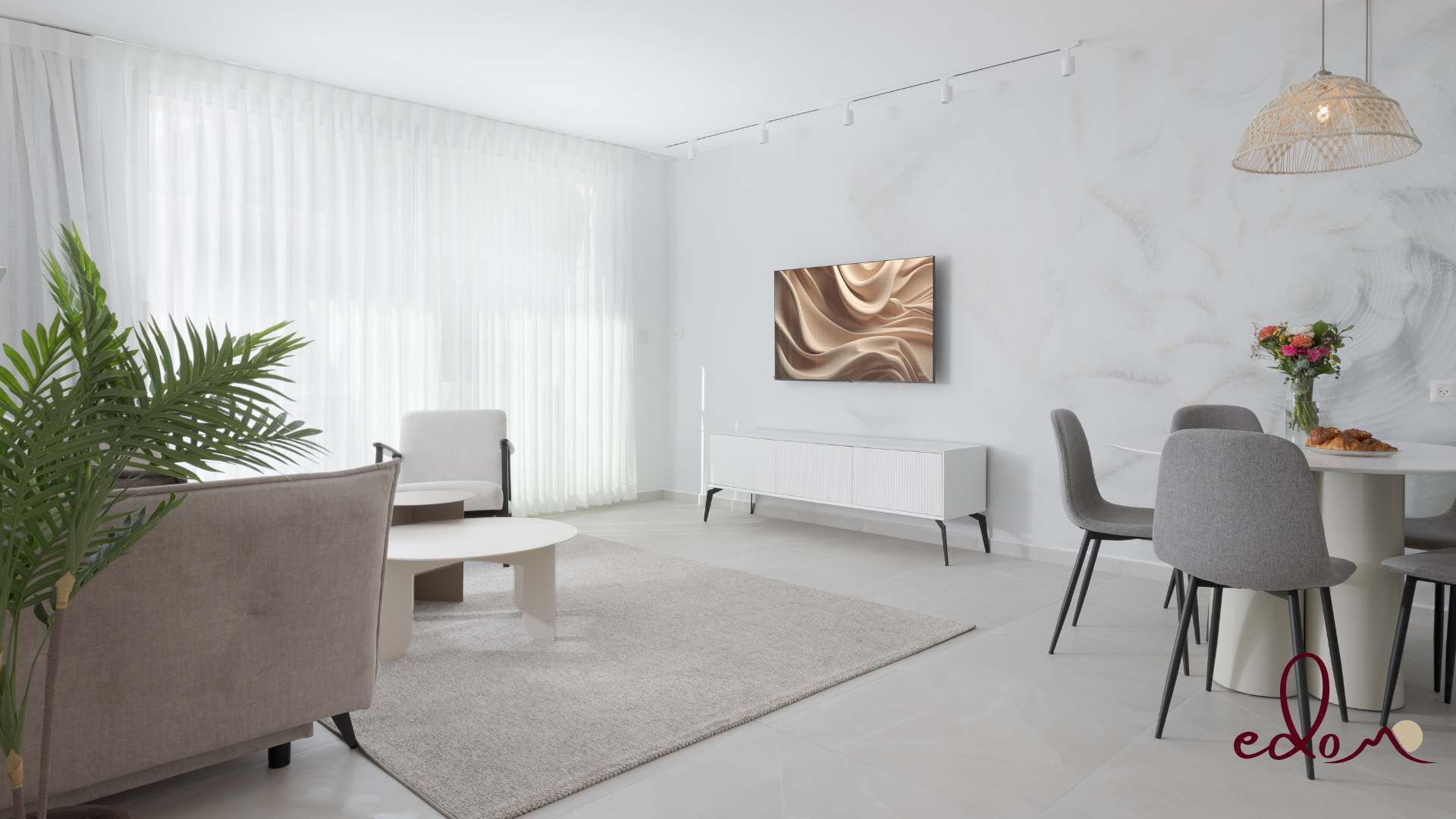 En moderne stue med spiseområde, der indeholder en hvid sofa, et spisebord med stole, en radiator og et stort abstrakt billede på væggen.