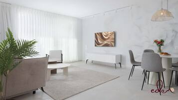 En moderne stue med spiseområde, der indeholder en hvid sofa, et spisebord med stole, en radiator og et stort abstrakt billede på væggen.