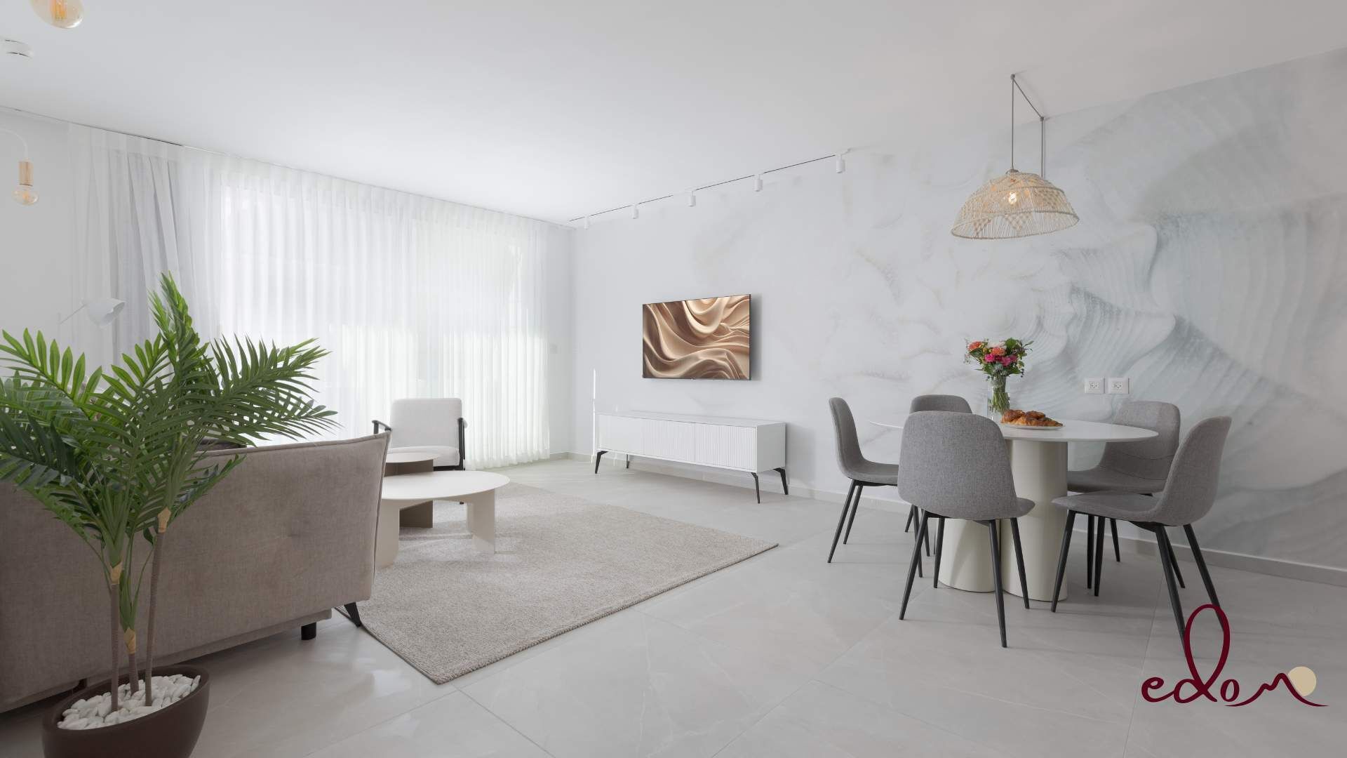 Una sala moderna con un sofá, una mesa de comedor con sillas, una planta en maceta y una obra de arte colgada en la pared.