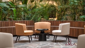 A seating area with two armchairs and a round table, surrounded by lush greenery. - דירה משפחתית במתחם סי סייד  - By Edomlux (Eilat)