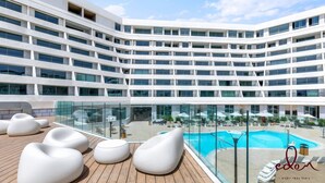 A modern hotel with multiple floors, a rooftop pool area with lounge chairs, and a glass-enclosed pool. - דירה משפחתית במתחם סי סייד  - By Edomlux (Eilat)