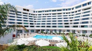 A modern hotel with a central pool, multiple balconies, and outdoor seating areas. - דירה בסי סייד עם נוף מדהים לים - By Edom (Eilat)
