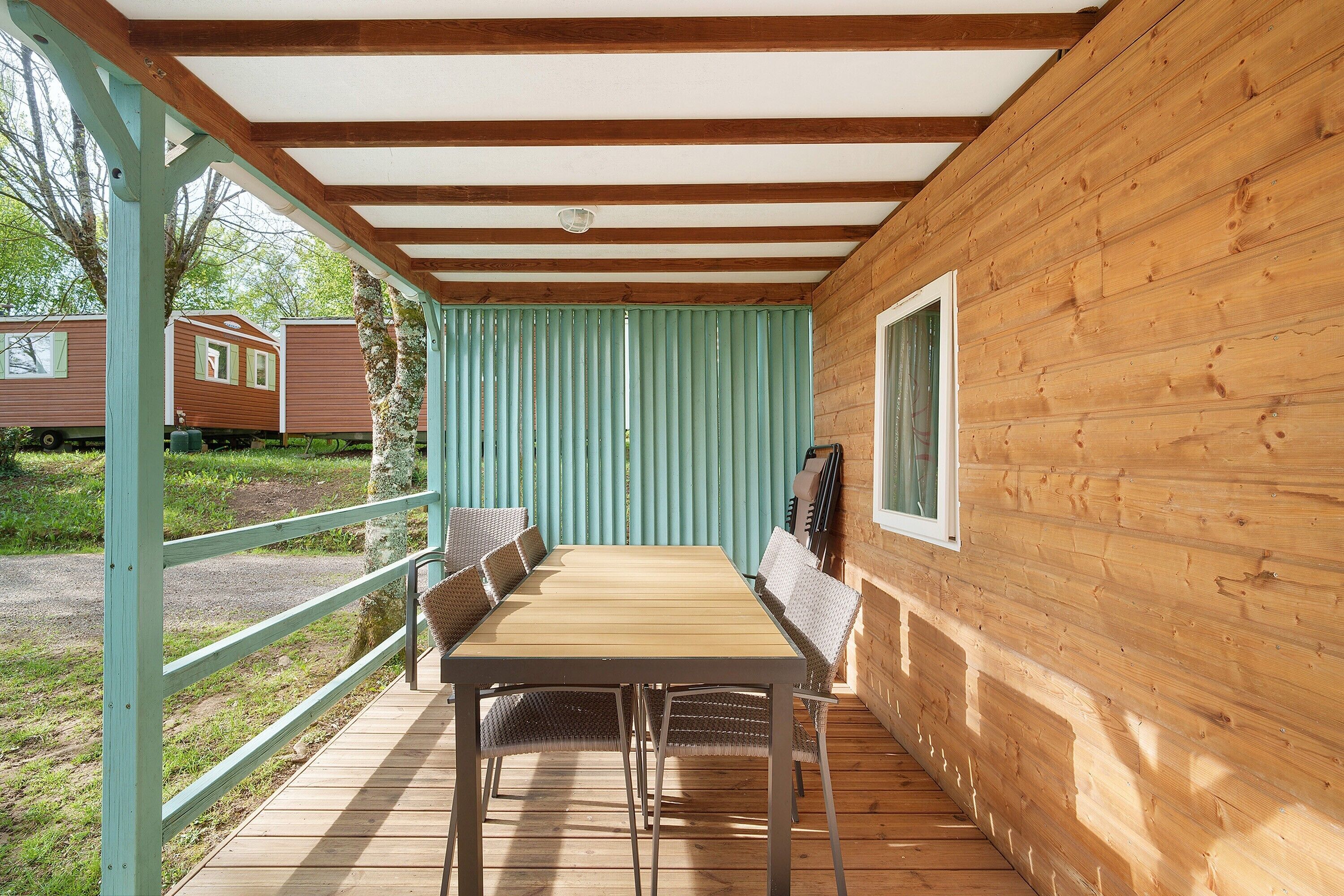 Une cabane en bois avec une table et des chaises, une fenêtre et une vue sur une autre cabane.