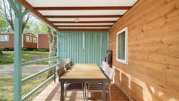 Une cabane en bois avec une table et des chaises, une fenêtre et une vue sur une autre cabane.