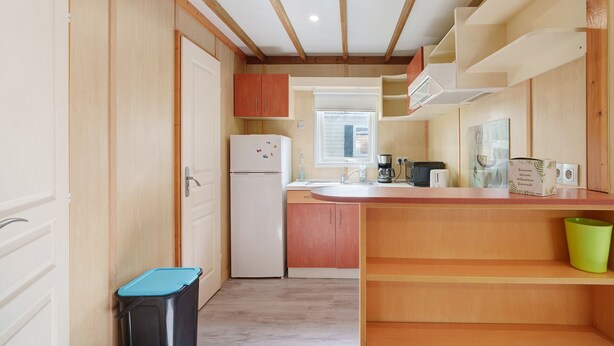 Una cocina con armarios de madera, un refrigerador blanco, un lavamanos y una ventana.