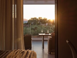 Ein Balkon mit Korbmöbeln, zwei Gläser Weißwein und ein Tisch für zwei Personen.