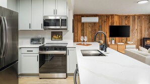 A modern kitchen with stainless steel appliances, a built-in oven, and a large island. - The Writer's Cottage - 13m to Shenandoah NP, Hot Tub, Mountain Views, EV (Luray)