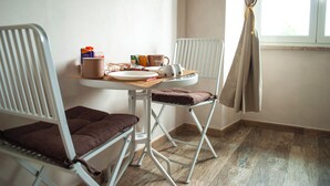 A room with a dining table set for two, a chair, a window with curtains, and a radiator. - QT suite & luxury (Rome)