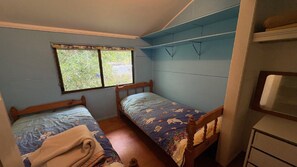 Un alojamiento pequeño y de una sola habitación con dos camas de madera, una ventana y un escritorio empotrado.