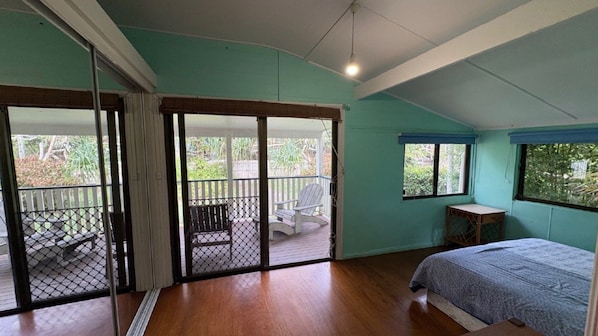 A bedroom with a bed, a window, a door leading to a balcony, and a small table.