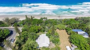 An aerial view of a coastal area with a beach, vegetation, and buildings.