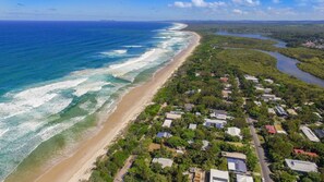 Una zona residencial costera con casas a lo largo de la playa y un río que discurre paralelo a la costa.