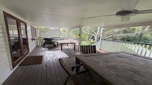 A covered porch with a grill, a table, and a bench. - By The Sea - by Lifestyle. Brunswick Heads (NEW BRIGHTON)
