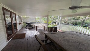 A covered porch with a grill, a table, and a bench. - By The Sea - by Lifestyle. Brunswick Heads (NEW BRIGHTON)