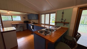 A compact kitchen with wooden countertops, a sink, and a dining area with a table and chairs.