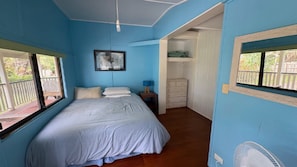 A bedroom with a bed, a nightstand, a dresser, and a fan.