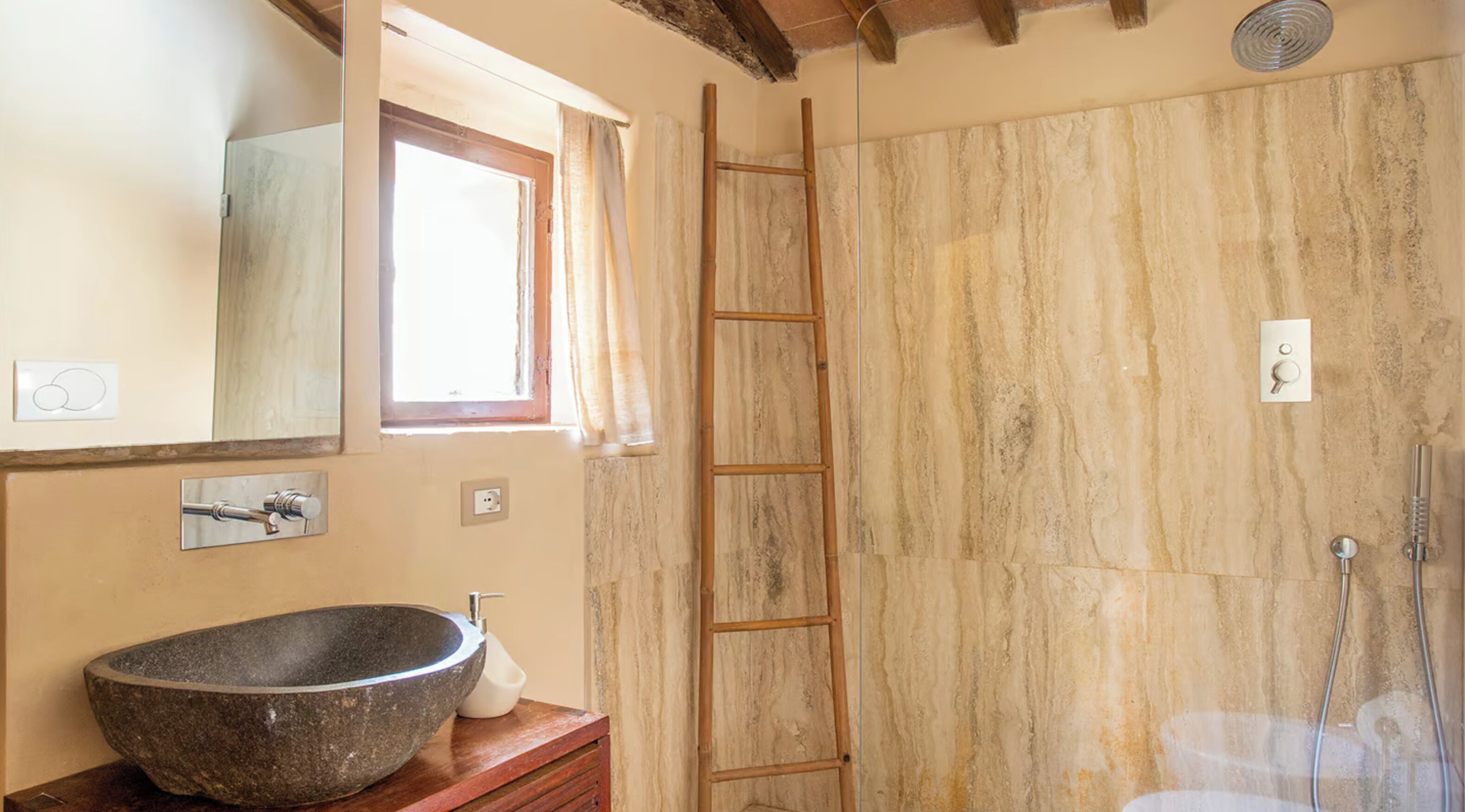 Un baño con un lavabo de piedra, una escalera de madera y una ducha.