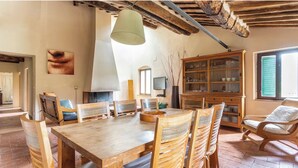 Un comedor rústico con una mesa y sillas de madera, una lámpara colgante y un armario de madera con puertas de cristal.