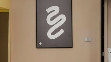 Una obra de arte abstracta en marco sobre una pared color beige en una habitación de hotel.