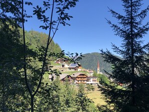 A mountain village with traditional wooden houses, a church, and a clear blue sky. - Traditional Apartment "Waldstille" in Idyllic Nature, Balcony and Wi-Fi (San Lorenzo di Sebato)