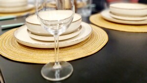 Una mesa de comedor con platos apilados y una copa de vino, sobre una mesa negra con un mantel tejido.
