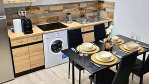 Una cocina moderna con armarios de madera, horno integrado, lavadora y comedor para cuatro.