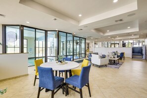 A modern hotel lobby with a round dining table, blue and yellow chairs, a sofa, and a fireplace. - 3BR Beachfront PH Suite: Suntide III - Unit 1203 (South Padre Island)