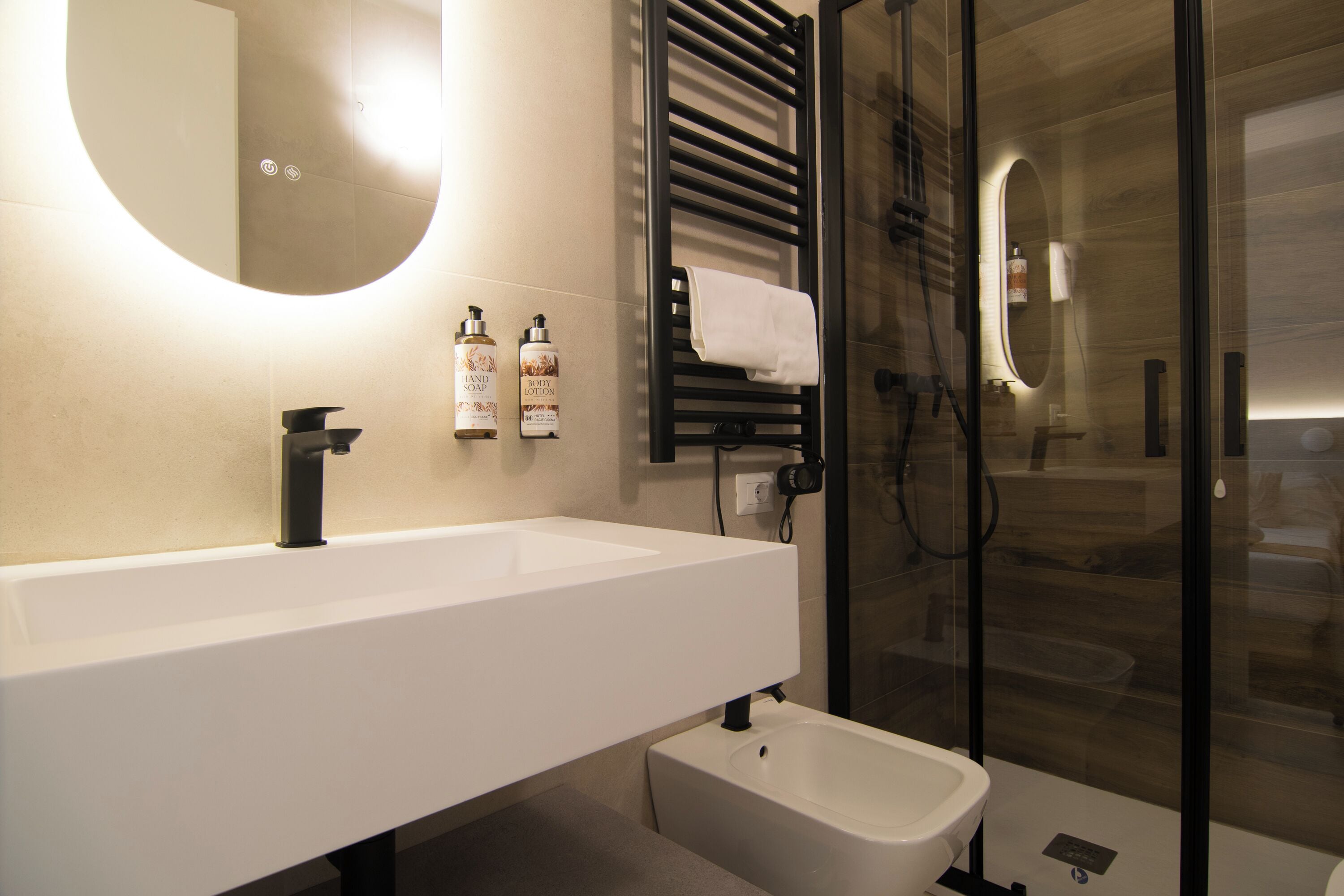A modern bathroom with a white sink, a bidet, and a glass shower enclosure.